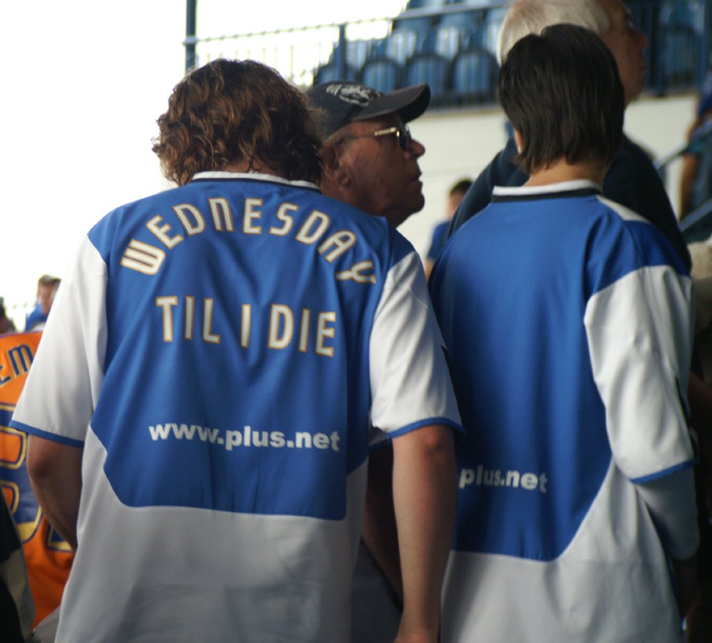 Supporters wearing Sheffield Wednesday shirts, viewed from behind.